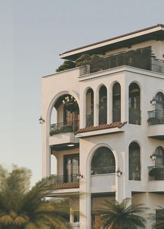 a large white building with balconies and balconyes on the second floor is surrounded by palm trees