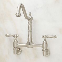 a faucet with two handles on a marble wall