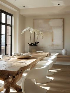 a wooden table with white chairs in front of a large window