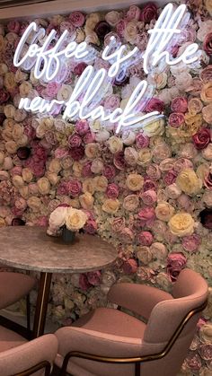 two chairs and a table in front of a floral wall