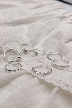 The Veronica Heart Ring Set is a charming collection of seven rings, available in silver or gold and sized at 7. This versatile set includes a variety of designs to suit any style: one ring features an open heart, two rings showcase rhinestone hearts, one plain band offers simplicity, one band is adorned with sparkling rhinestones, one chainlink band adds a unique touch, and one notched band completes the set. Perfect for mixing and matching, the Veronica Heart Ring Set is a delightful way to ac Valentines Basket, Clear Purses, Faux Leather Purse, Two Rings, Studded Necklace, Curated Closet, Plain Bands, Gold Ring Sets, Faux Leather Belts