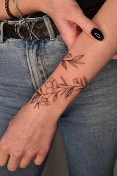 a woman with a flower tattoo on her left arm and right hand is holding onto the wrist