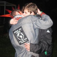 two young men hugging each other outside at night