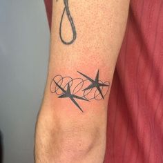 a man with a tattoo on his arm has scissors and a hook in the middle