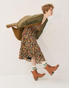 a woman in a floral dress and brown boots