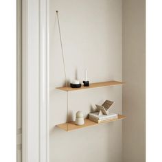 two wooden shelves with books, candles and other items on them in a white room