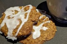 two oatmeal cookies with icing on a table next to a coffee cup