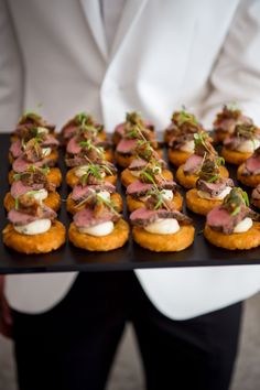 a person holding a tray with small appetizers on it