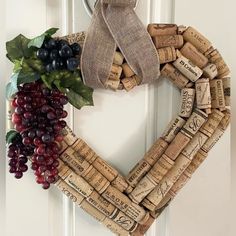 a heart shaped wreath made out of wine corks with grapes and leaves on the front door