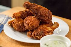 some fried food on a white plate next to a small bowl of ranch dips