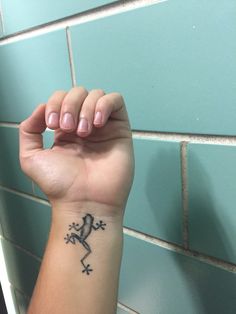 a person's arm with a lizard tattoo on it, in front of a blue tile wall