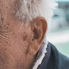 an old man with white hair is looking off into the distance