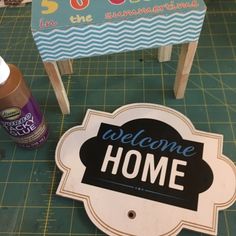 a welcome home sign sitting on top of a cutting board next to a bottle of sunscreen