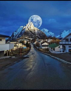 a full moon rises over a mountain range in the distance, with houses on either side