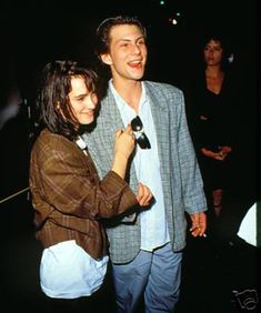 a man standing next to a woman in front of a crowd at an event and smiling