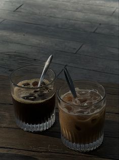 two drinks sitting on top of a wooden table next to each other with spoons in them