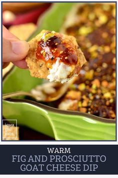 a hand holding up a cracker over a casserole dish