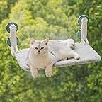 two cats laying on a swing in the middle of some trees and bushes with one cat looking at the camera