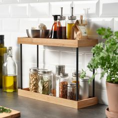 two wooden shelves filled with spices and condiments next to a potted plant