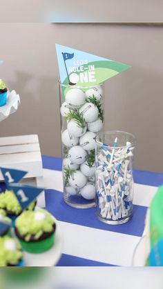 a table with cupcakes and golf balls in a clear vase on top of it