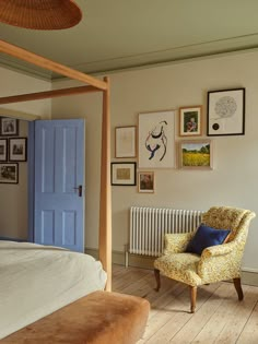 a bedroom with a bed, chair and pictures on the wall