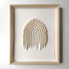 an art piece made out of white folded paper in a wooden frame on the wall