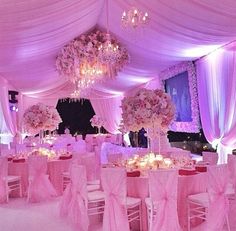 the tables are covered with pink linens and decorated with flowers, candles and chandeliers