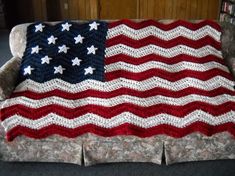 an american flag crocheted afghan on a couch in a living room with dark carpeting