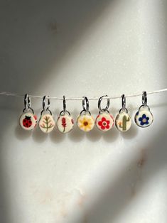 five flower charms hanging from a line on a white surface with shadows coming through the window