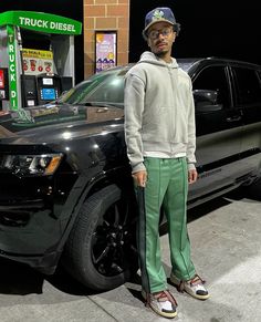 a man standing in front of a black jeep parked next to a vending machine