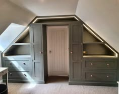 an attic bedroom with built - in closets and shelves, along with a desk