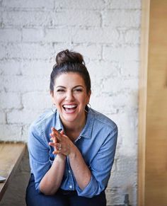 a woman sitting on the ground smiling and holding her hands together