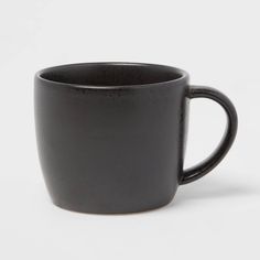 a black coffee cup sitting on top of a white table