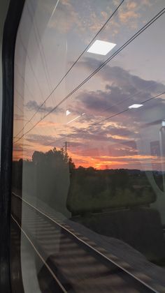 the sun is setting on the horizon as seen through a train's window at dusk