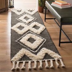 a black and white runner rug with tassels on the floor next to a bench