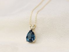 a necklace with a blue tear shaped stone hanging from it's gold plated chain