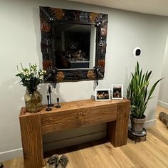 a wooden table sitting in front of a mirror on top of a hard wood floor