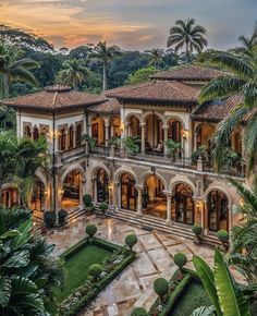 an aerial view of a mansion with palm trees and greenery in the foreground