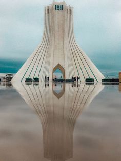 people are standing in front of a large building that looks like it has been built into the water