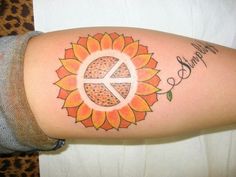 a woman's arm with a sunflower and peace sign tattooed on the side