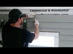 a man in black shirt and white gloves painting the side of a building with grey siding