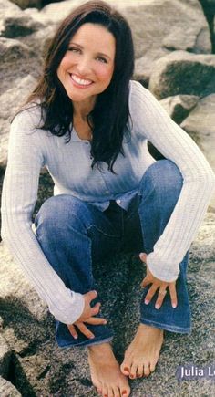 a woman is sitting on some rocks and smiling