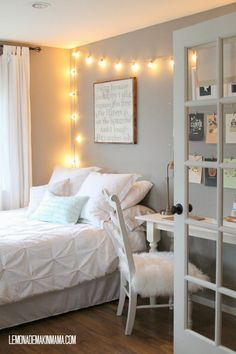 a white bed sitting in a bedroom next to a window with lights on the wall