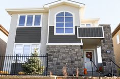 a gray house with white trim and windows on the front door is seen in this image