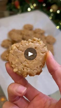 a person holding up a cookie in front of a christmas tree with cookies on it