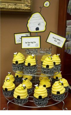 cupcakes with yellow frosting and decorations are on display in front of a teddy bear