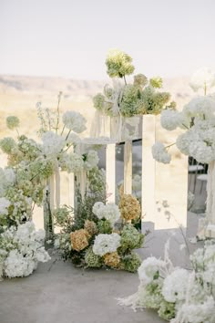 white flowers and greenery are arranged in vases