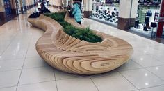 a wooden bench sitting on top of a tiled floor in a store filled with people