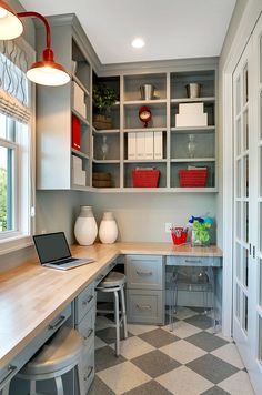 a laptop computer sitting on top of a wooden desk in a room with lots of cabinets