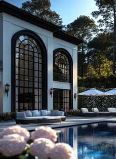 an outdoor swimming pool with lounge chairs and umbrellas next to the house in the background